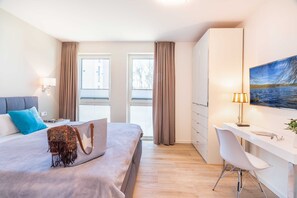 Una camera d'albergo moderna con un letto, una scrivania e ampie finestre.