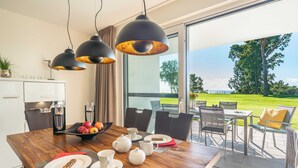 A modern kitchen with a wooden dining table set for breakfast, featuring a fruit bowl, teapots, and cups. - Terrace apartment Haffblick - Oasis on the lagoon - Haffblick (6-2) (Garz)