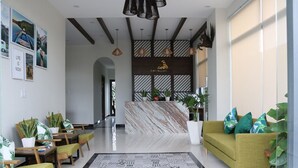 A modern lobby with a reception desk, seating area, and a large patterned rug. - ENTIRE VILLA#11BEDROOMS#ROOFTOPPOOL#danangbayview (Đà Nẵng)