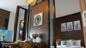 A hotel room with a dining area, a bed with decorative pillows, and artwork on the walls. - ENTIRE VILLA#11BEDROOMS#ROOFTOPPOOL#danangbayview (Đà Nẵng)