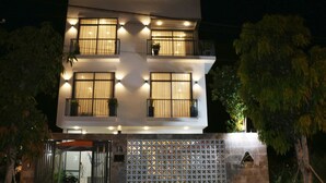 A modern two-story building with multiple windows and balconies, featuring a gated entrance and a decorative wall with a lattice pattern. - ENTIRE VILLA#11BEDROOMS#ROOFTOPPOOL#danangbayview (Đà Nẵng)