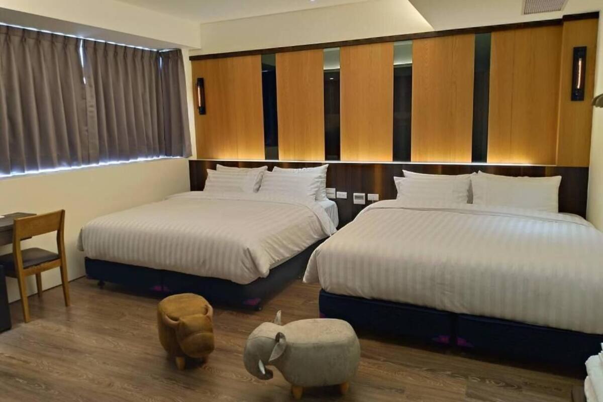 Une chambre d’hôtel avec deux lits, un bureau et une chaise.