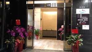 L’entrée d’un hôtel, avec des portes en verre, des plantes en pot et un comptoir d’accueil à l’intérieur.