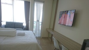 A hotel room with a bed, a TV mounted on the wall, a desk, and a chair. - Menteng Park By The Jones (Jakarta)