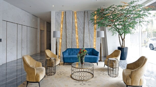 A lobby with a blue sofa, two armchairs, a coffee table, and a large potted plant. - Menteng Park By The Jones (Jakarta)