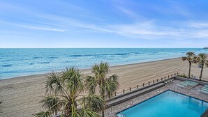 Ein Poolbereich mit Blick auf Strand und Meer.