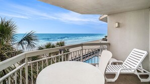 Ein Balkon mit Pool, weißen Liegestühlen und Blick auf das Meer.