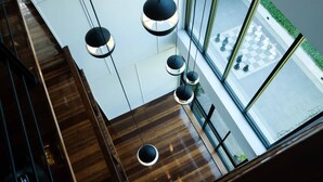 Een modern interieur met houten vloeren, een trap en hanglampen.