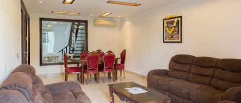 A living room with two sofas, a coffee table, and a dining area with chairs and a table.