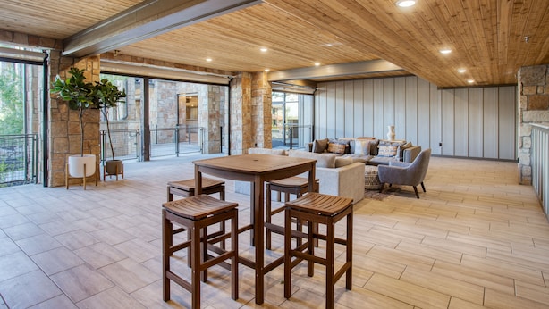 Un salón amplio con techo de madera, paredes de piedra y un gran ventanal con vistas al exterior.