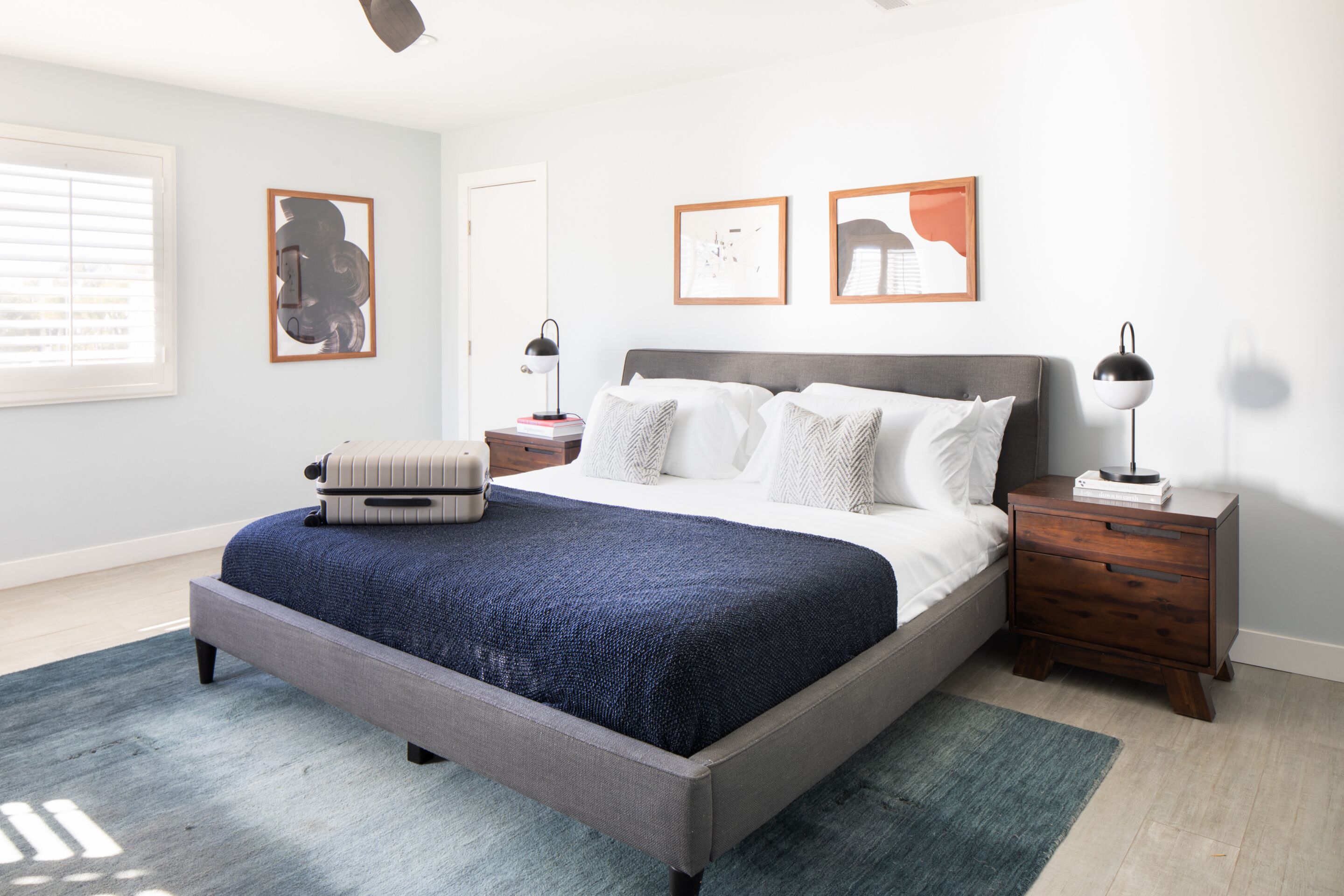 A modern bedroom with a large bed, bedside tables, and artwork on the walls.