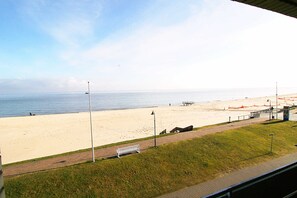 Una playa con un paseo marítimo pavimentado, bancos y una vista distante del océano.