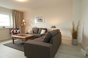 A living room with a sofa, a coffee table, a TV, and a lamp.