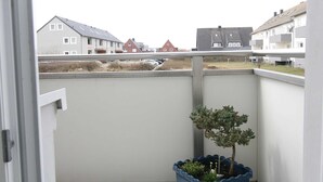 A balcony with a potted plant, overlooking a residential area with houses. - Budersand 26, Germany (Hörnum (Sylt))