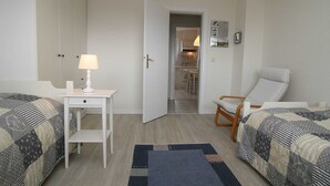 A bedroom with two beds, a desk with a lamp, a chair, and a rug. - Budersand 26, Germany (Hörnum (Sylt))