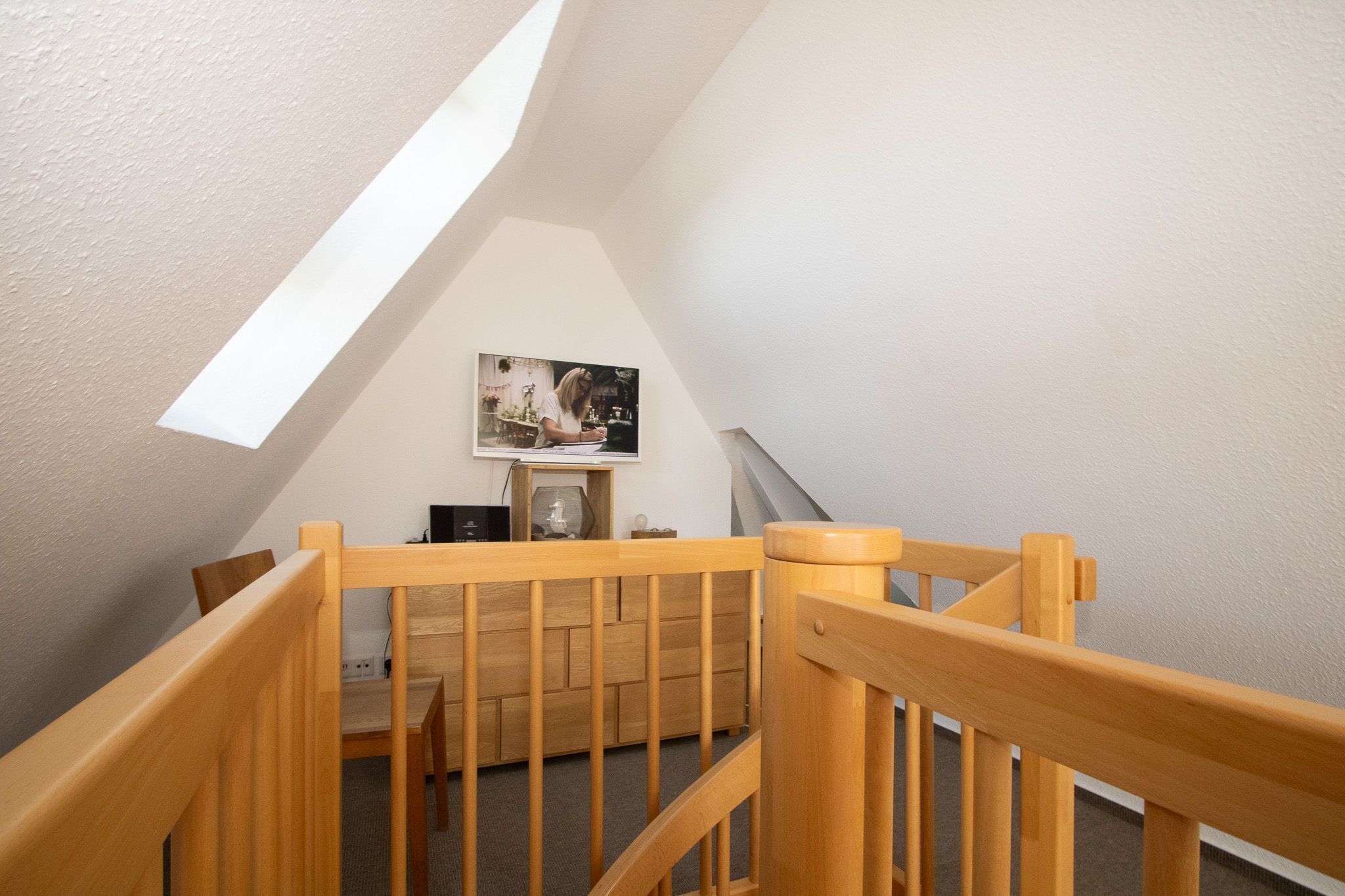A wooden staircase with a view of a dining area and a framed picture on the wall.