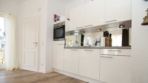 Eine moderne Küche mit weißen Schränken, einer Edelstahl-Dunstabzugshaube und einem eingebauten Backofen.