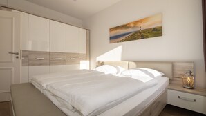Ein Schlafzimmer mit einem großen Bett, einem Kleiderschrank, einem Nachttisch mit Lampe und einem Bild an der Wand.