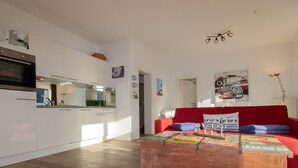 Eine moderne Küche mit weißen Schränken, einem roten Sofa und einem Couchtisch mit Zeitschriften.