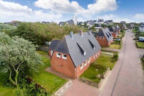 Un quartier résidentiel avec des maisons en briques, une allée pavée et, au loin, le clocher d’une église.