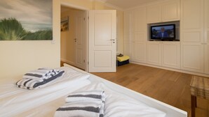 Et hotelværelse med en seng, et fjernsyn og et maleri på væggen.