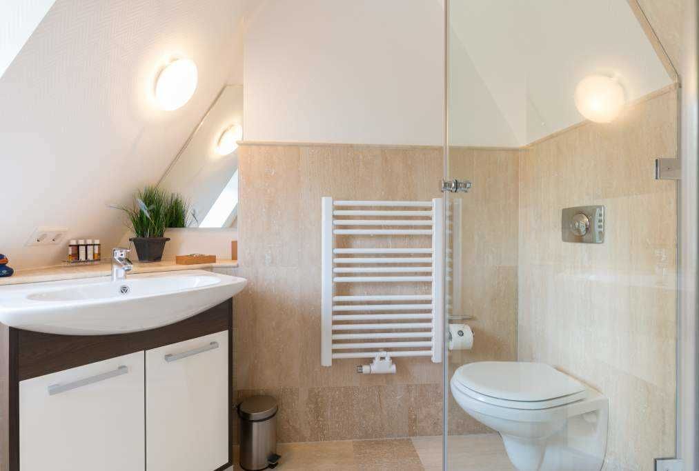 Un baño moderno con cabina de ducha de vidrio, un lavamanos blanco y un inodoro.