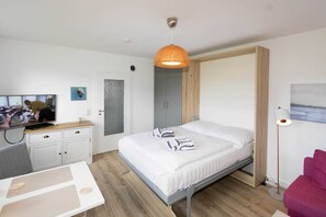 Ein modernes Hotelzimmer mit Bett, Schreibtisch, Fernseher und Kleiderschrank.