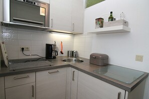 Eine moderne Küche mit Edelstahlgeräten, einem eingebauten Backofen, einer Kaffeemaschine und einer Kochinsel mit Glasplatte.