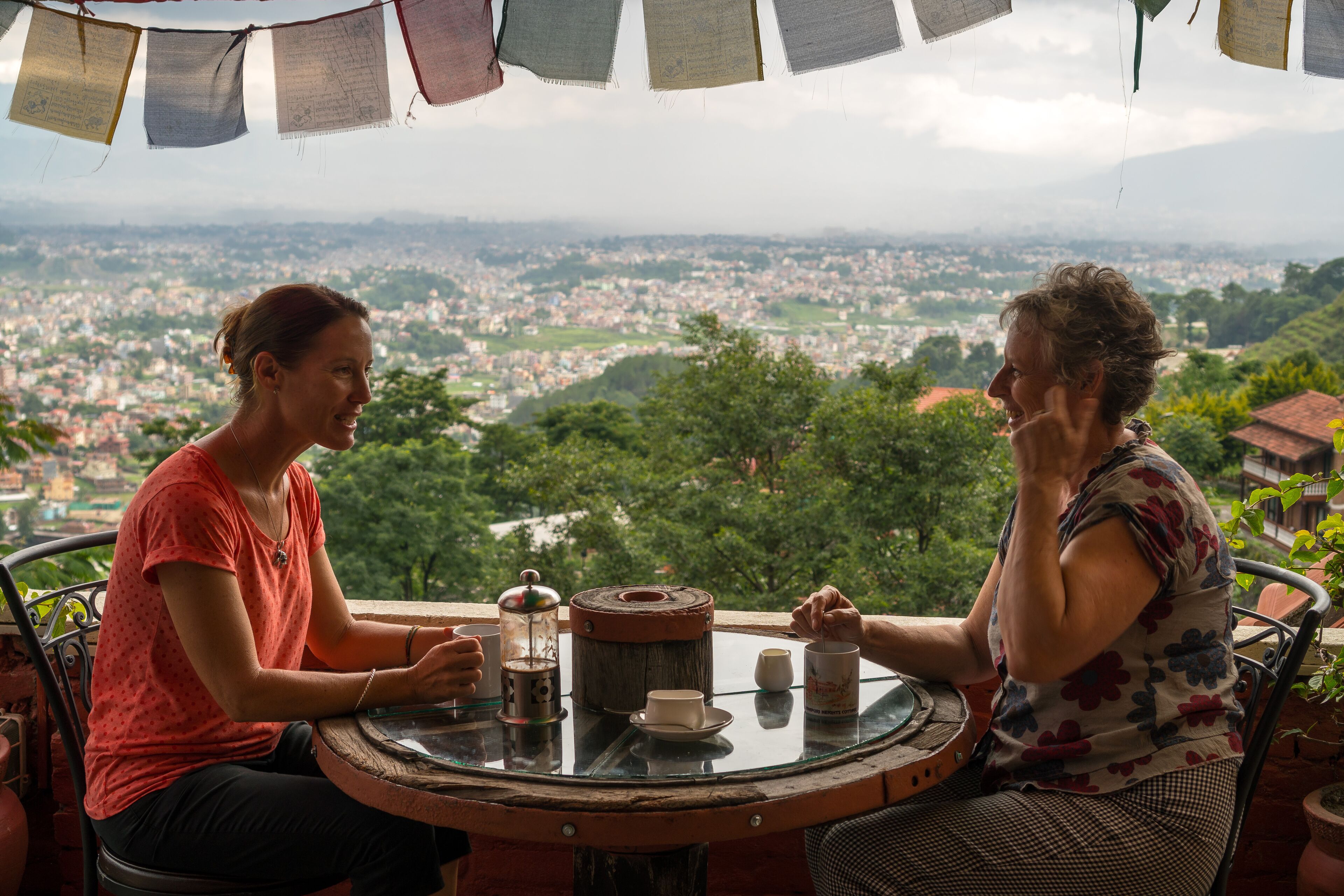 Two people sitting at a round table with a view of a cityscape.