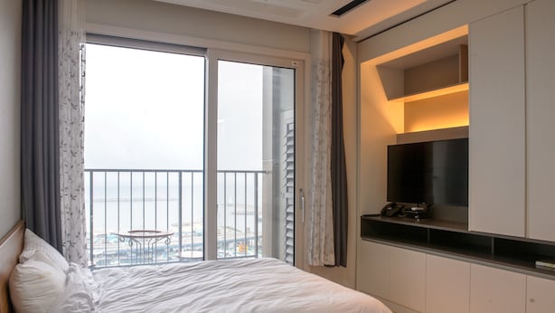 Une chambre d’hôtel avec un lit, une télévision, une petite table et un balcon donnant sur la ville.