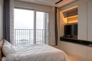 Une chambre d’hôtel avec un lit, une télévision, une petite table et un balcon donnant sur la ville.