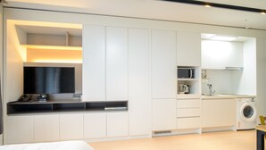 Une chambre d’hôtel moderne dotée d’un grand lit, d’un bureau intégré avec un téléviseur à écran plat, d’un four à micro-ondes, d’un mini-réfrigérateur et d’une machine à laver.