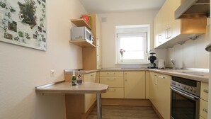 Eine kleine Küche mit Holzausstattung, einer eingebauten Mikrowelle und einem Edelstahlbackofen.
