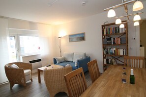 A cozy living room with a sofa, chairs, a wooden table, and a bookshelf.