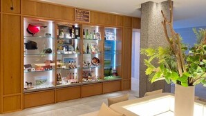 A reception area with a wooden display cabinet filled with various items, a seating area with a sofa, and a large potted plant. - Bibai ekimae hotel BIJIKO (Bibai)