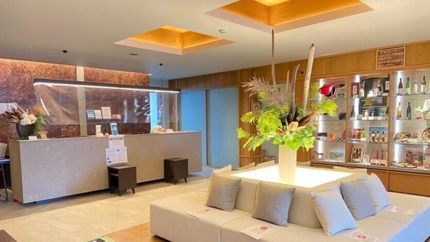 A modern hotel lobby with a reception desk, a seating area, and a display of amenities. - Bibai ekimae hotel BIJIKO (Bibai)
