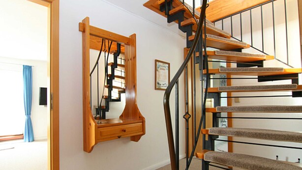 Eine Treppe mit Holzdielen und einem Metallgeländer, die zu einer oberen Etage führt.
