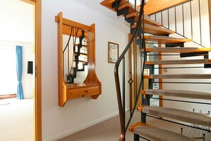 A staircase with wooden steps and a metal railing, leading to an upper floor.