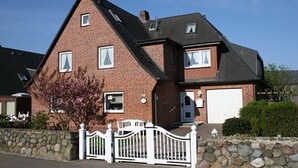 Ein zweistöckiges Ziegelhaus mit Steinmauer, weißem Zaun und Garage.