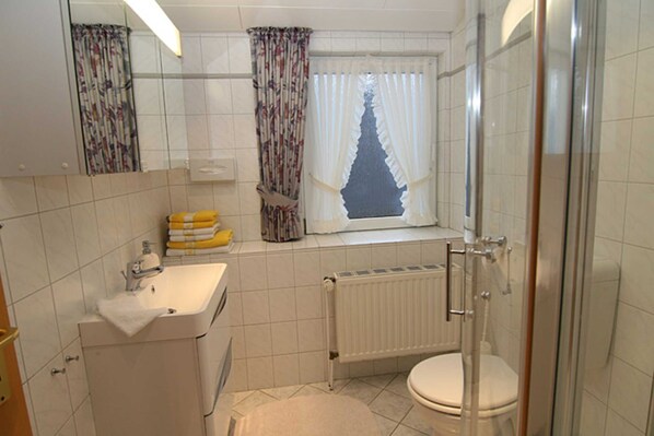 A bathroom with a toilet, sink, and shower.