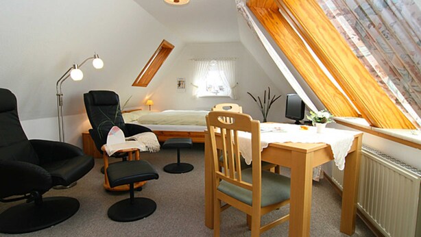 A small, cozy room with a sloped ceiling, a bed, a desk with a chair, a lamp, and a window with curtains. - House Gräpel App. 5, Germany (Hörnum (Sylt))