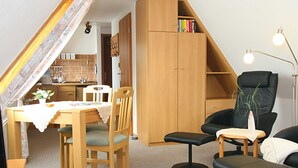 A cozy, well-lit room with a dining table, chairs, a bookshelf, a black office chair, and a small desk with a lamp. - House Gräpel App. 5, Germany (Hörnum (Sylt))