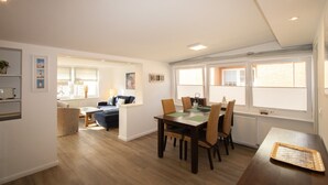 Een ruime woonkamer met een eettafel, stoelen en een bank.