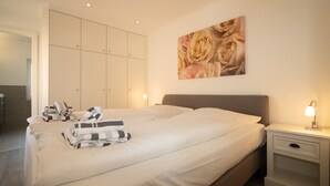 Een hotelkamer met een groot bed, een nachtkastje met een lamp, een garderobe en een muur met een bloemschilderij.