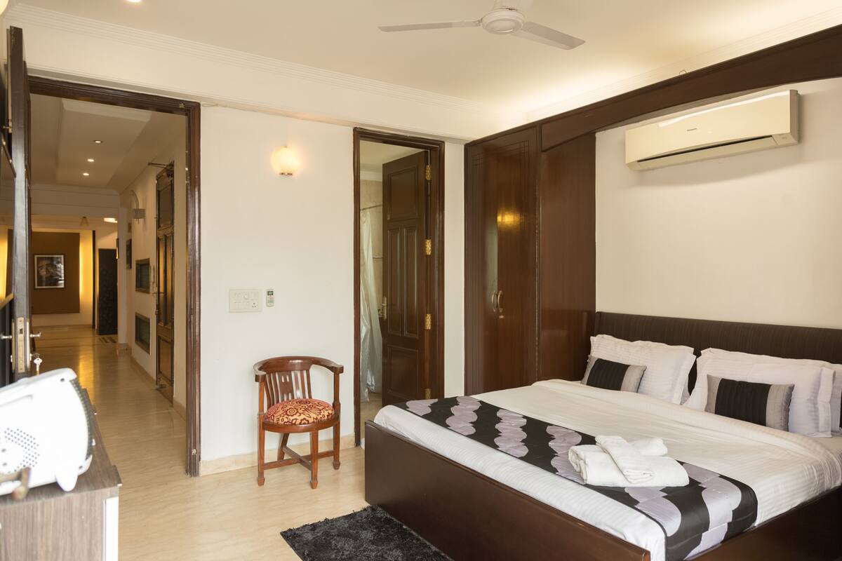 Une chambre d’hôtel avec un grand lit, une chaise, un bureau et un appareil de climatisation.