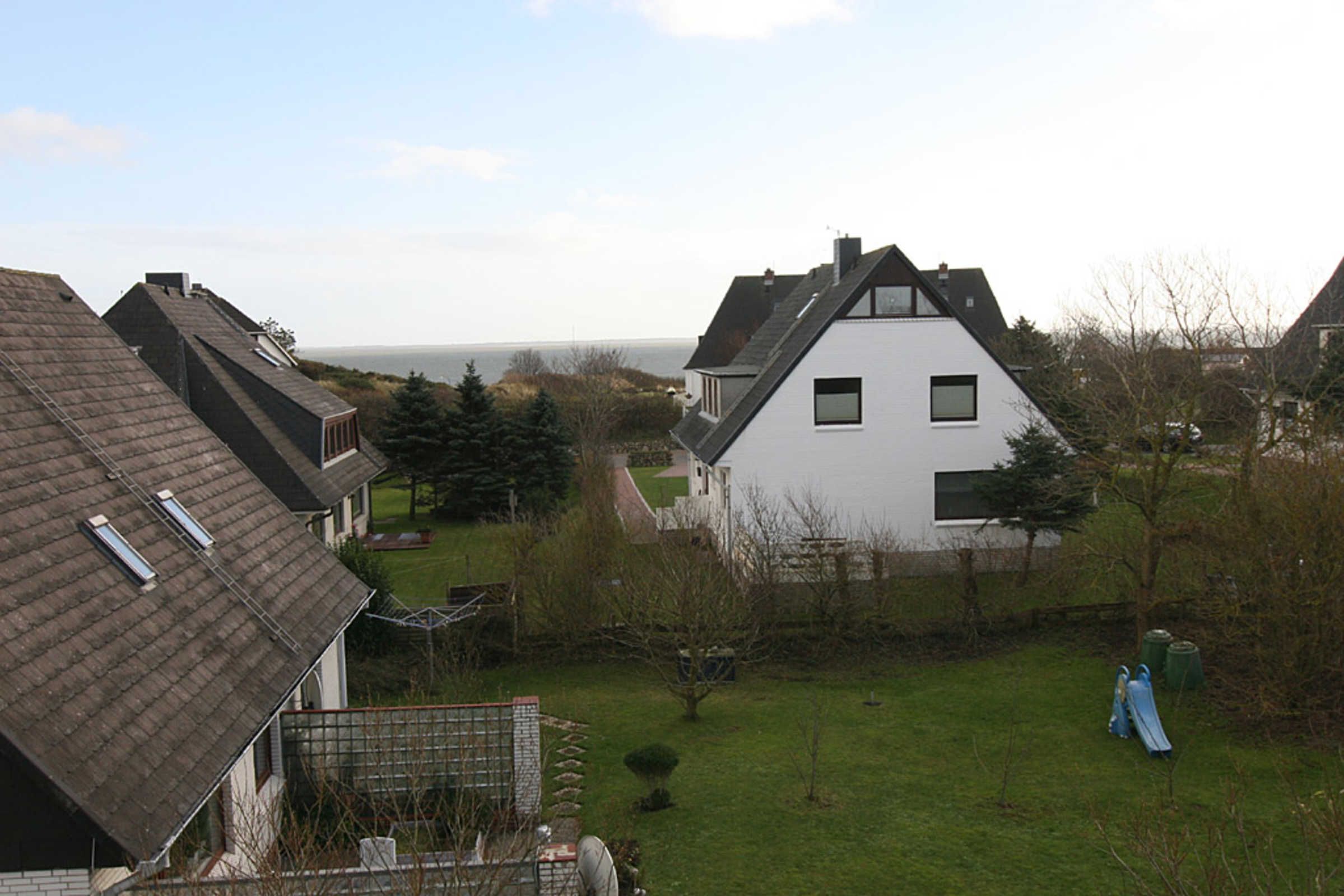 Bairro residencial com casas, gramado e vista para o mar.