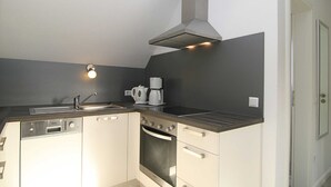 A compact kitchen with a built-in dishwasher, oven, and a stainless steel range hood. - House Schössler apartment 2 (Hörnum (Sylt))