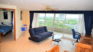 A hotel room with a balcony, a sofa, a dining table, and a chair. - 1 bed at Angket Hip Residence (Pattaya)