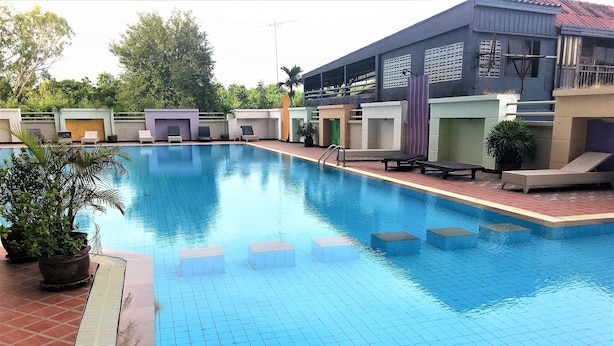 A swimming pool with tiled steps leading into the water, surrounded by lounge chairs and potted plants. - 1 bed at Angket Hip Residence (Pattaya)