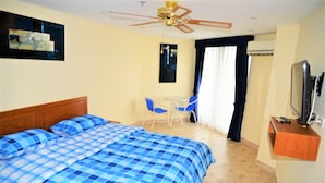 A hotel room with a bed, a desk, a chair, a ceiling fan, and a TV. - 1 bed at Angket Hip Residence (Pattaya)